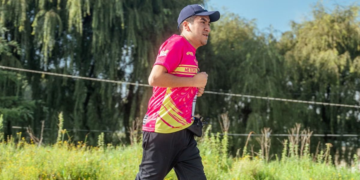 A man in a colorful shirt jogging in a rural area, focusing on endurance and fitness.