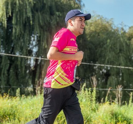 A man in a colorful shirt jogging in a rural area, focusing on endurance and fitness.